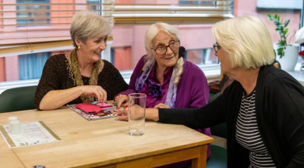 A group of older women sat around a table in discussion