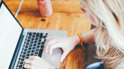 A woman typing on a laptop at a table.