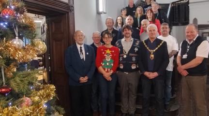 A gathering of people at Kendal Town Hall beside a Christmas tree