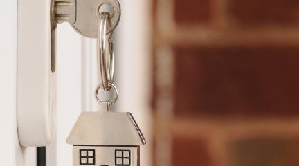 Key and keyring with house-shaped pendant in a white door