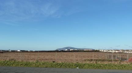 A flat, grassy field with Black Combe in the background.