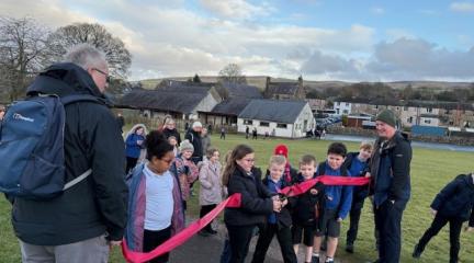 A girl cutting a ribbon in a playground.