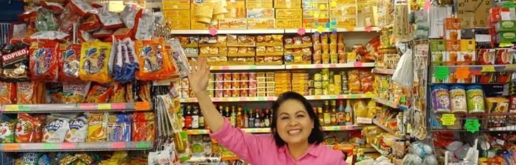 A woman in a pink top standing in front of a food stall.