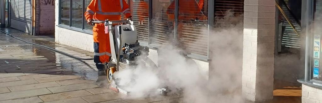 A man using a chewing gum removal machine on a pavement.