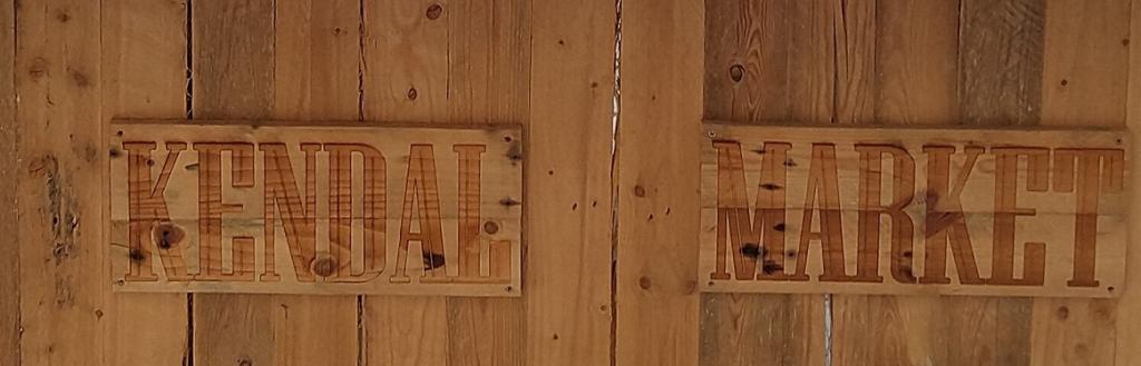 A wooden stall with the words "Kendal Market" on the side.