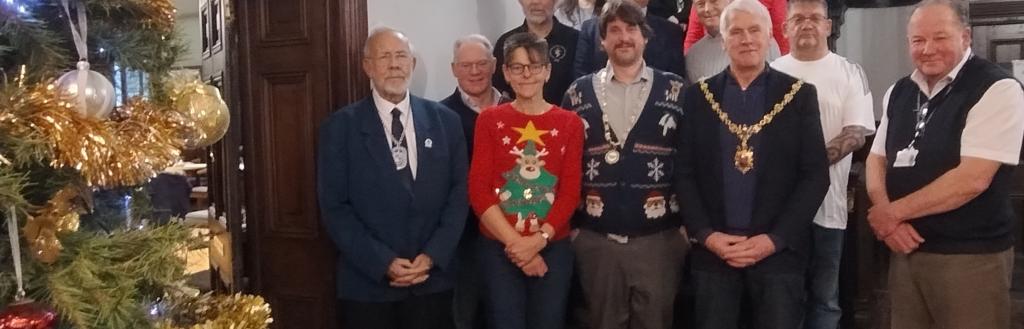 A gathering of people at Kendal Town Hall beside a Christmas tree