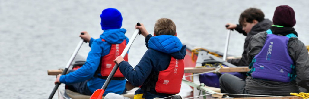 Young people in protective equipment enjoying a paddle boat on a lake