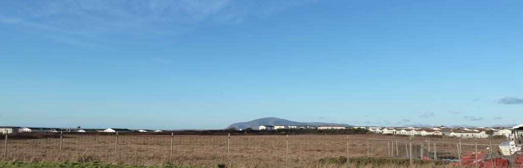 A flat, grassy field with Black Combe in the background.