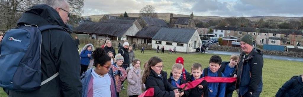 A girl cutting a ribbon in a playground.